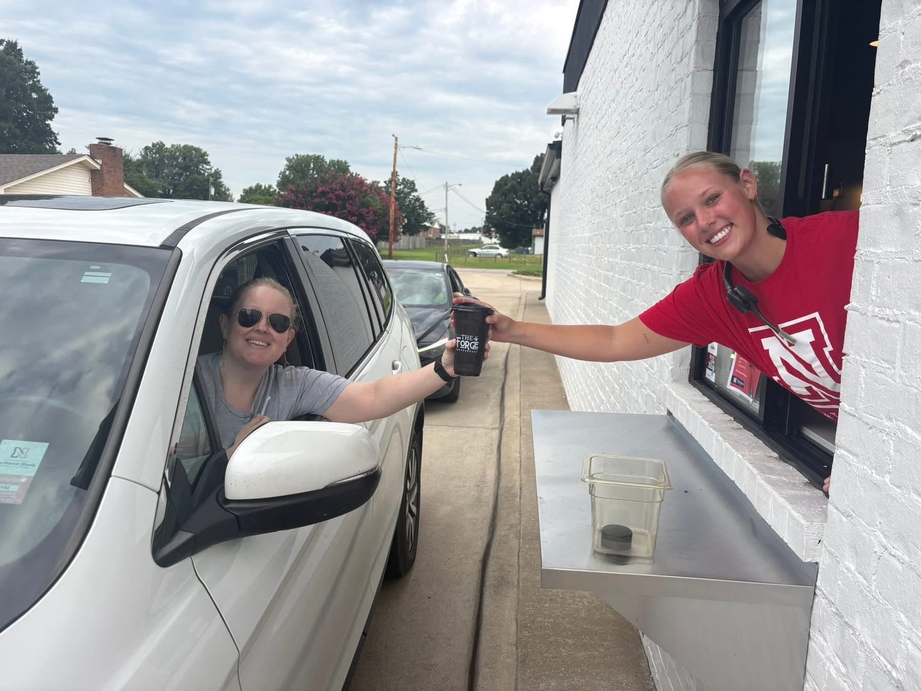 Barista handing a Forge Coffeehouse drink through the drive-thru window