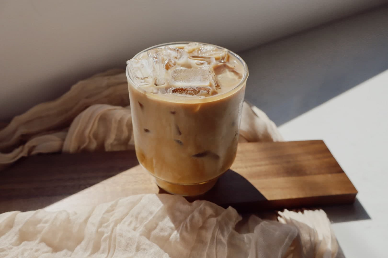 Iced latte with large ice cubes on a wooden board